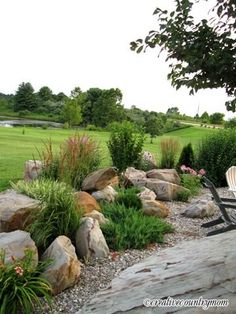 a bench sitting on top of a lush green field next to a stone wall covered in plants