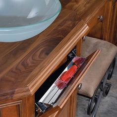 a bathroom sink sitting under a wooden counter top next to a bowl on a chair