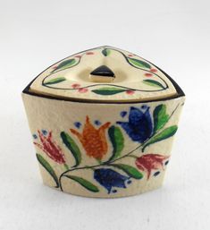 a ceramic container with flowers painted on the outside and inside, sitting on a white surface