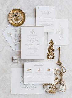 the wedding stationery is laid out on top of each other, including an ornate brooch