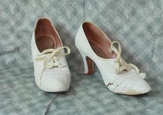 One pair of very cute Antique circa 1940s 1950s white Leather Woman's Shoes.  The shoes feature a very cute pierced detail & original silky rayon laces.    Perfect Wedding-Nurse Athletic Shoes. Period Costume. These shoes are in AS FOUND vintage condition, one of the shoes has significant damage-as shown.  I am selling for study, repair or restoration.   Bottom soles are leather, they do show wear.    Approx Measurements- 9" heel to toe exterior measurement 2 3/4" across bottom sole at widest point,2 3/4 inch heel- these measurements are taken on the outside of the shoes. Please check out the photos as this is part of the description.  They are still sturdy and wearable for the right size foot or would make a great prop.  There are no returns due to size, fit or color-Please ask questions. Vintage Reinforced Heel Court Shoes, Vintage White Round Toe Heels, 1910s Shoes, 1940s Shoes Women Low Heel, 1930 Womens Shoes, 1930’s Shoes, 1950s Shoes, 1940s Shoes, White Leather Shoes