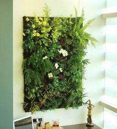 a green wall mounted to the side of a building with flowers and plants on it