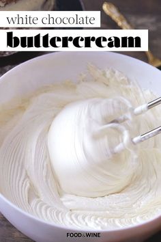 a bowl filled with white frosting next to a cake on top of a table