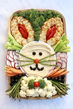 a platter filled with vegetables, veggies and a face made to look like a cat