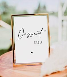 a wooden table with a sign that says dessert on it and a feather sitting next to it