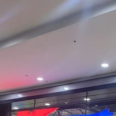 an airplane is parked in front of a building with red and blue flags hanging from it's ceiling