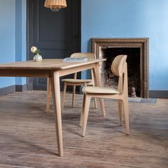 a wooden table and two chairs in front of a fire place with a blue wall