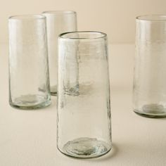 three clear glass vases sitting on top of a white tablecloth covered flooring