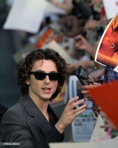 a man in black suit and sunglasses holding up his cell phone to take a picture