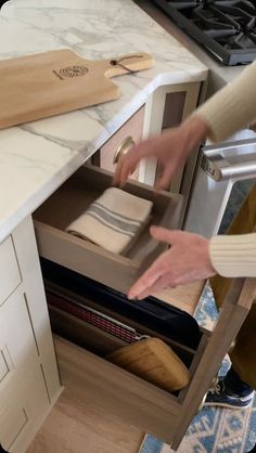 a person reaching into an open drawer in a kitchen