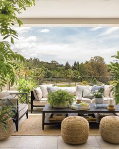 a living room filled with furniture and lots of greenery on top of a wooden floor