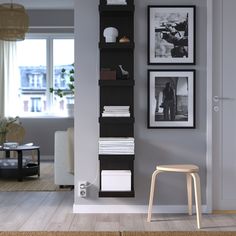 a living room with pictures on the wall and a chair in front of a bookshelf