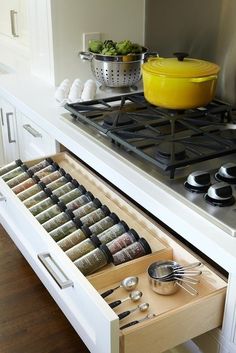 an open drawer in the middle of a stove with spices and utensils on it