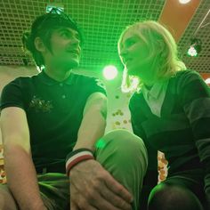 a man and woman sitting next to each other in front of green lights on the ceiling