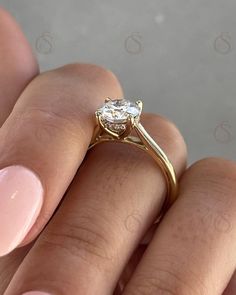 a woman's hand holding a ring with a diamond on it