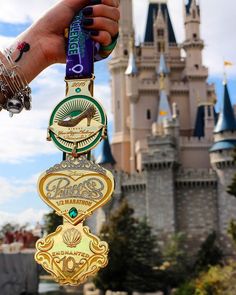 a person holding up a medal in front of a castle with the name disney on it