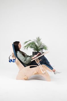 a woman sitting in a chair with a laptop on her lap and a potted plant