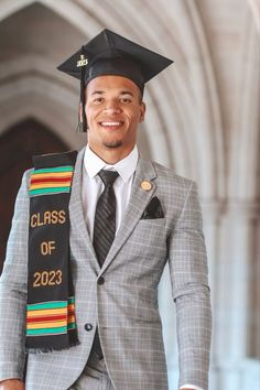 a man in a suit and tie is smiling for the camera with his graduation stole around his neck