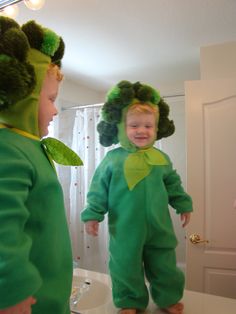 two children in green costumes standing on a bathroom counter