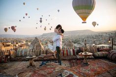 a woman standing on top of a pile of pillows next to a hot air balloon