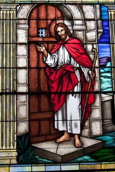 a stained glass window with jesus standing in front of a door and holding a staff