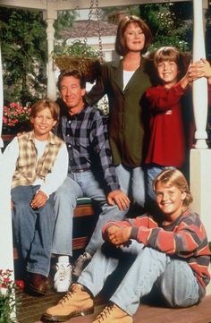 a group of people sitting on top of a porch next to each other and posing for a photo