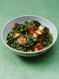 a white bowl filled with food on top of a green table