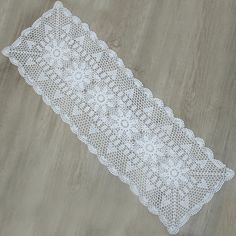 a white lace table runner sitting on top of a wooden floor