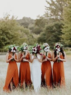 the bridesmaids are wearing orange dresses and holding bouquets in their hands while standing in tall grass