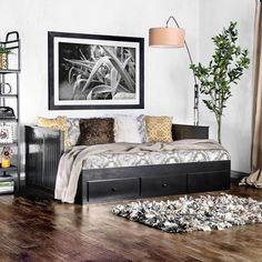 a bedroom with wood floors, white walls and a black daybed in the corner