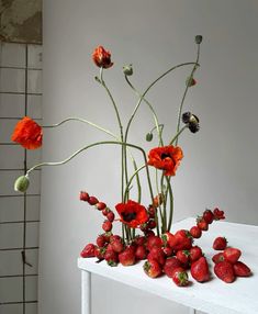 a white table topped with lots of red flowers and strawberries on top of it