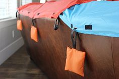 several orange and blue pieces of cloth hanging from the side of a brown wall with black clips on them