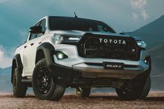 a white toyota truck parked on top of a dirt field