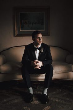 a man in a tuxedo sitting on a couch