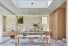 an open kitchen and dining room with white tile flooring, wooden furniture and large windows