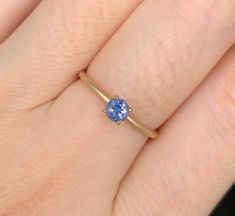 a woman's hand with a ring on it and a blue stone in the middle