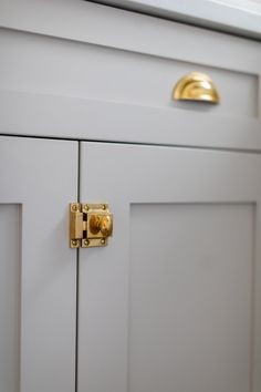 a close up of a door handle on a white cabinet with gold hardware and knobs