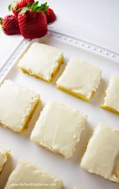 several squares of cake with white frosting and strawberries on the side