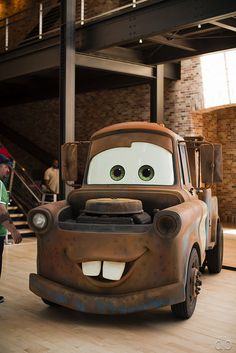 a man standing next to a car that is in the shape of mater from cars