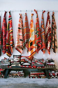 many colorful towels are hanging on the wall next to each other in front of a shelf