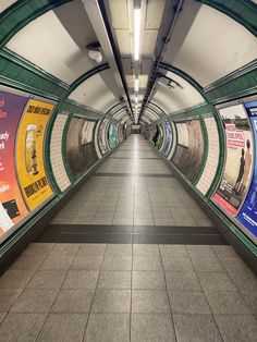 an empty subway station with posters on the walls and floor, as seen from the inside