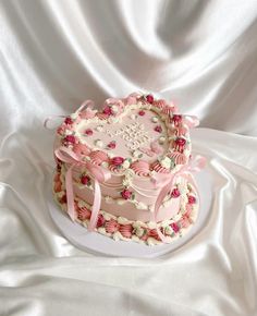 a pink cake decorated with flowers and ribbons on a white tableclothed cloth background