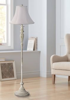 a white lamp sitting on top of a wooden floor next to a chair and window