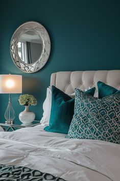 a bedroom with teal walls, white bedding and green accents on the headboard