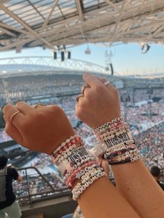 a person wearing bracelets at a baseball game with their hands up in the air