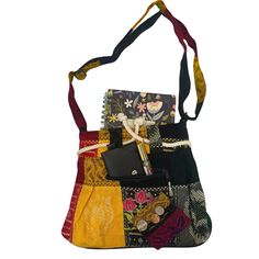 The colorful patchwork shoulder bag is a vibrant and eclectic accessory that exudes a bohemian charm. It's constructed from various fabrics with diverse patterns and colors, primarily featuring bold reds, sunny yellows, earthy greens, and stark black. The patchwork design creates a visually captivating mosaic, making each bag unique and one-of-a-kind. The front flap of the bag is adorned with an embroidered floral detail, adding a touch of delicate artistry to the overall design. The flap is secured with a rope drawstring closure, allowing for easy access to the bag's contents while also adding a rustic element to the overall aesthetic. A small zippered pouch, attached to the strap, provides extra storage for small essentials like keys or coins, adding a practical element to the bag's func Patchwork Hobo Shoulder Bag, Multicolor Patchwork Satchel Shoulder Bag, Multicolor Patchwork Tote Satchel, Patchwork Hobo Bag For Everyday Use, Colorful Patchwork Shoulder Bag For Daily Use, Multicolor Patchwork Satchel Bag, Multicolor Patchwork Tote Bag, Multicolor Square Hobo Bag For Daily Use, Square Multicolor Hobo Bag For Daily Use