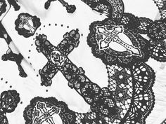 black and white photograph of crocheted lace with cross on it, as seen from above