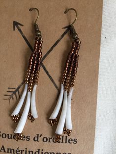 two pairs of earrings with white and brown beads hanging from the end of each ear