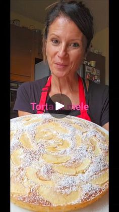 a woman with an apron is looking at a large pastry on a white platter