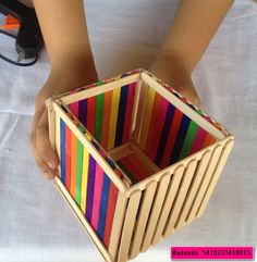 someone is holding a colorful box made out of strips of wood